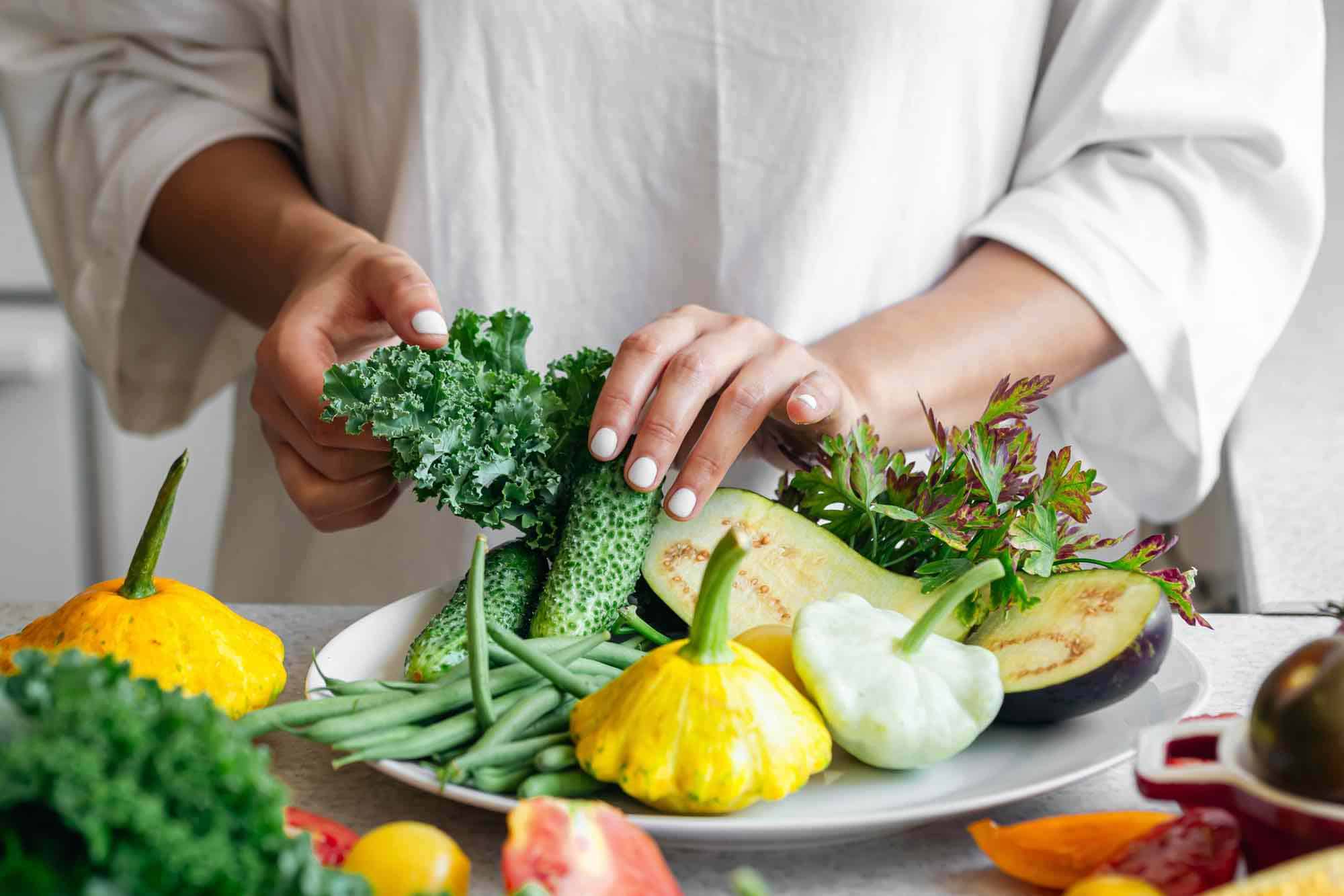 Frau legt rohkost ernährung frisches obst und gemuese auf teller