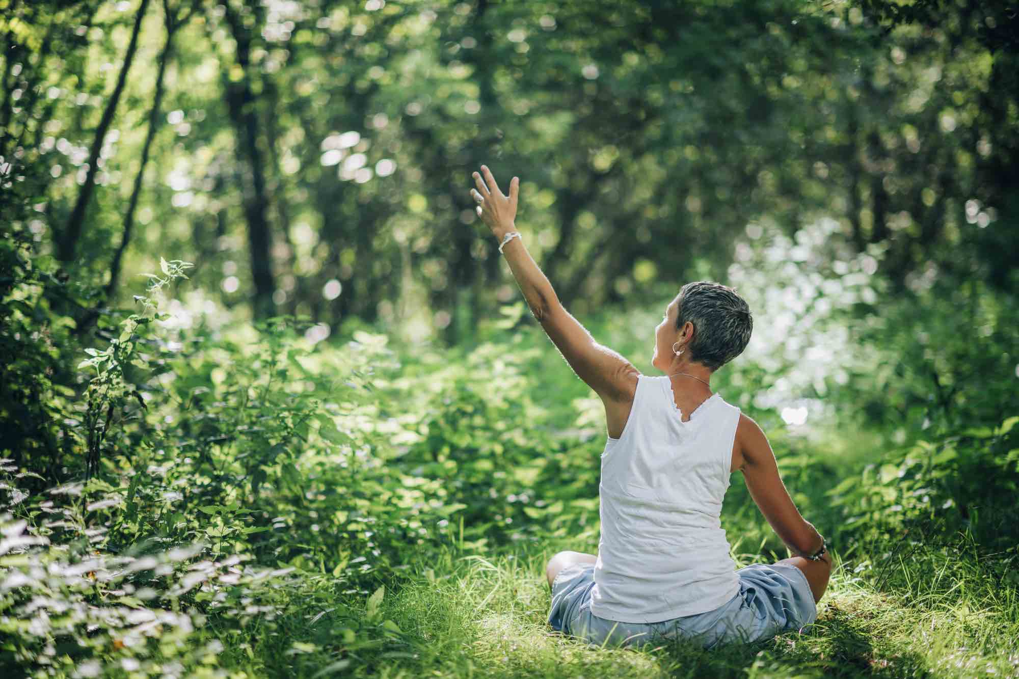 frau geniesst achtsamkeit im sommer durch meditation im wald