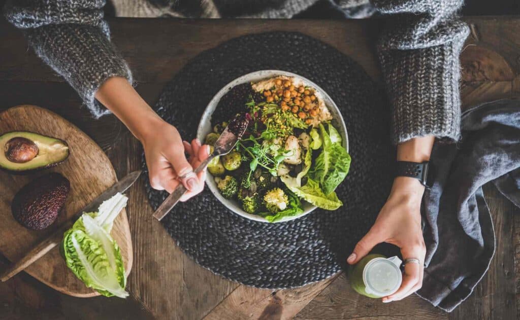 frau isst gesunde salatbowl mit gemüse basisches rezept