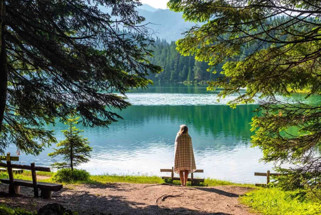 frau probiert waldbaden zum stressabbau in der natur und steht vor see