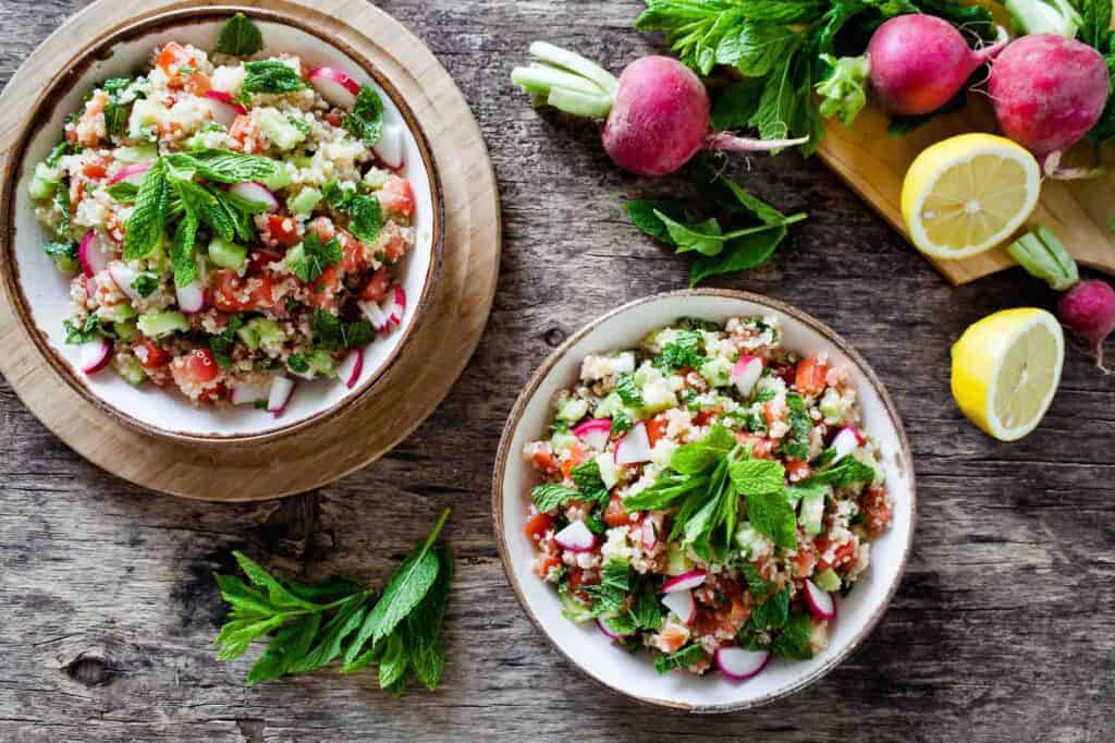 gesunde sommerbowl mit brennessel wildkräuter und tomate radieschen