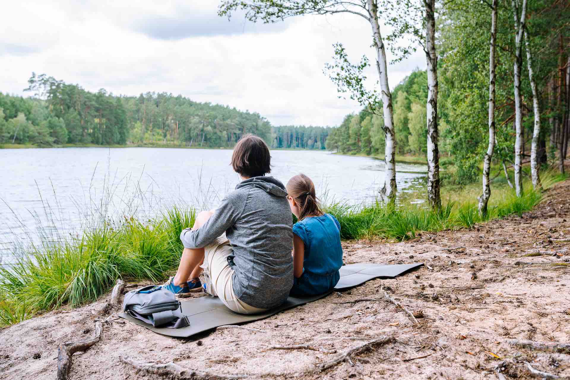 mutter und tochter bauen stress in der natur ab und sitzen am fluss